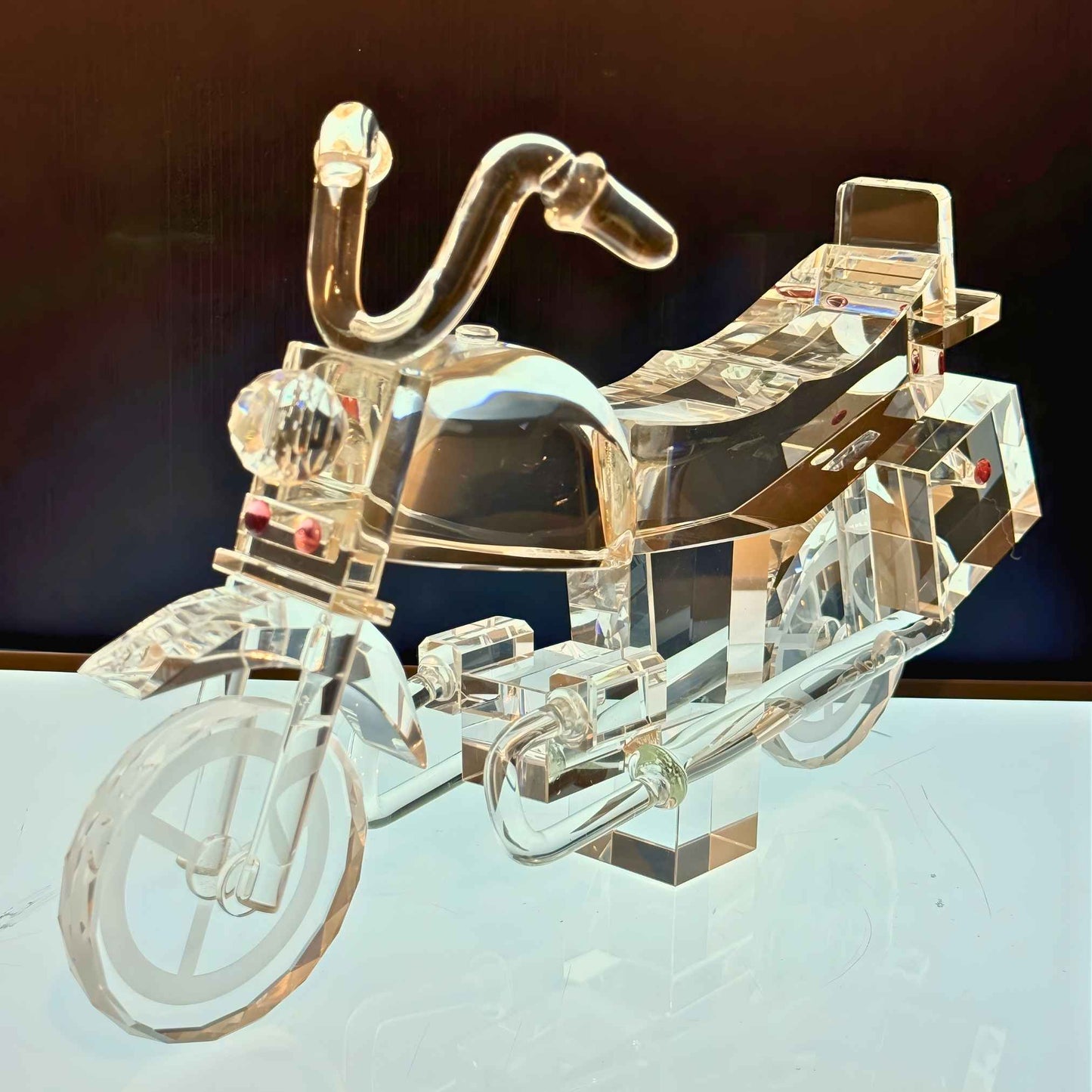 Clear crystal motorcycle model on a reflective surface with a dark background