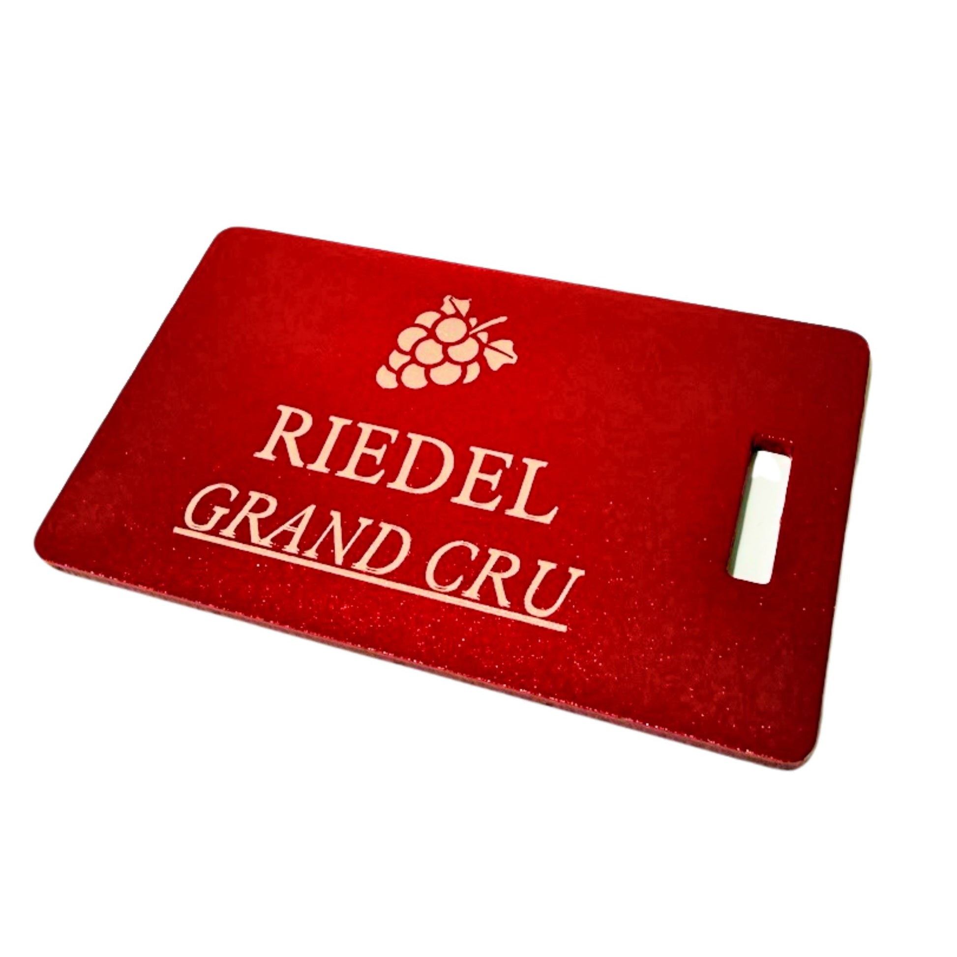 A red rectangular luggage tag with a handle cutout on the right, featuring a silver grape cluster logo and the text 'RIEDEL GRAND CRU' in gold on a white background.