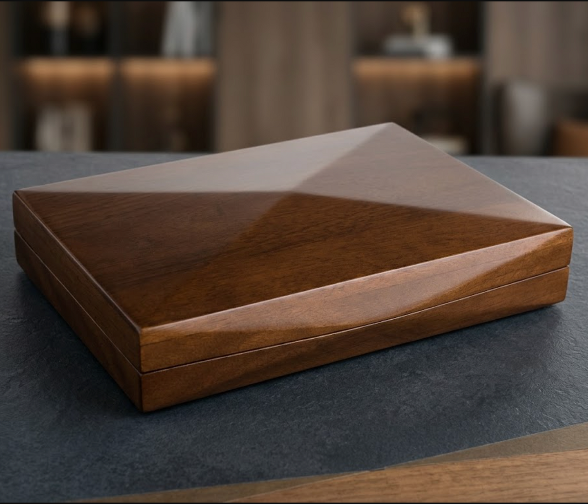 A square wooden box with a glossy finish, showcasing a geometric triangular pattern on the lid, set on a dark textured surface with a blurred background.