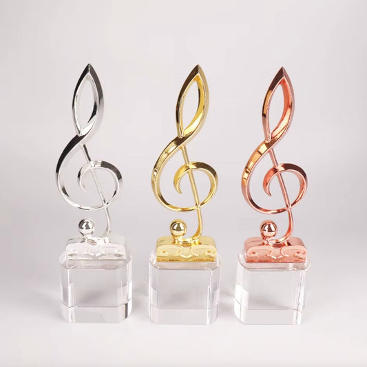 Three awards treble clefs in silver gold and rose gold on a white background 