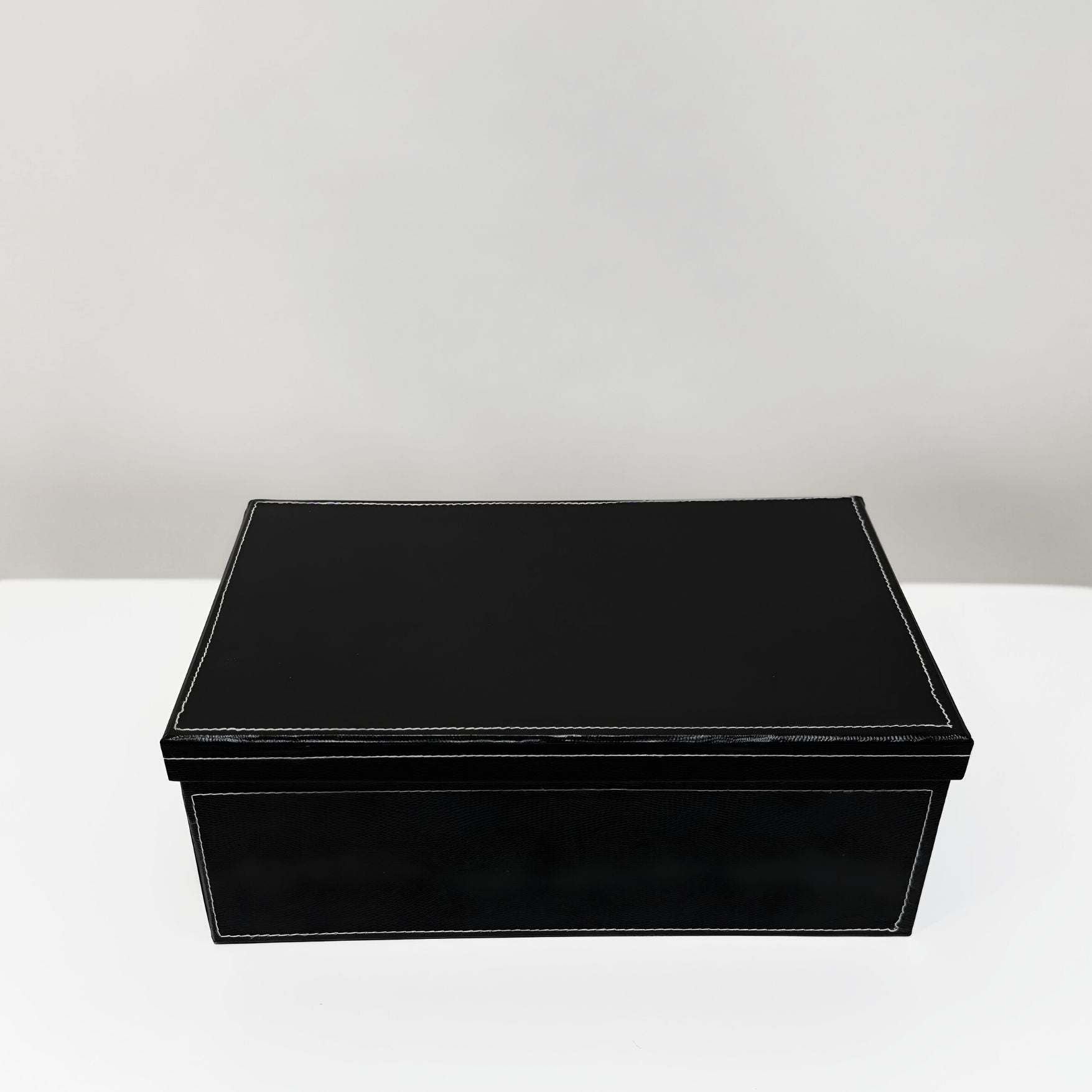 Black rectangular box on a white surface with a light gray background
