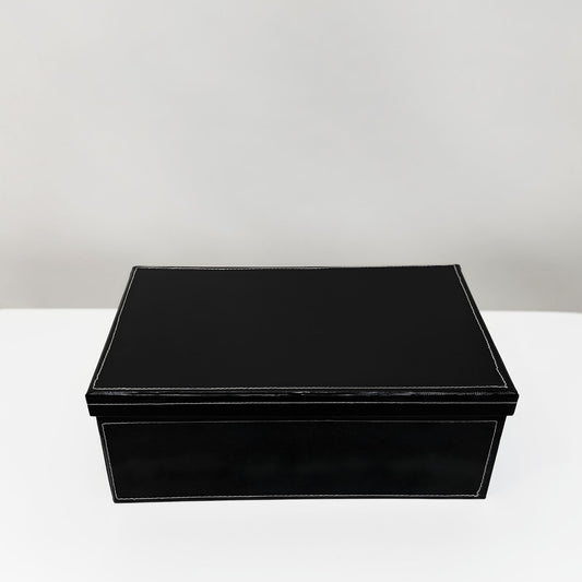 Black rectangular box on a white surface with a light gray background