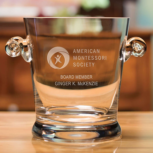 Clear glass ice bucket with engraved text on a wooden surface