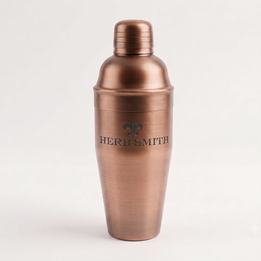 A brushed copper-colored metal cocktail shaker with a matching lid, featuring the text 'HERB SMITH' and a fleur-de-lis logo on the front, set against a plain light background.