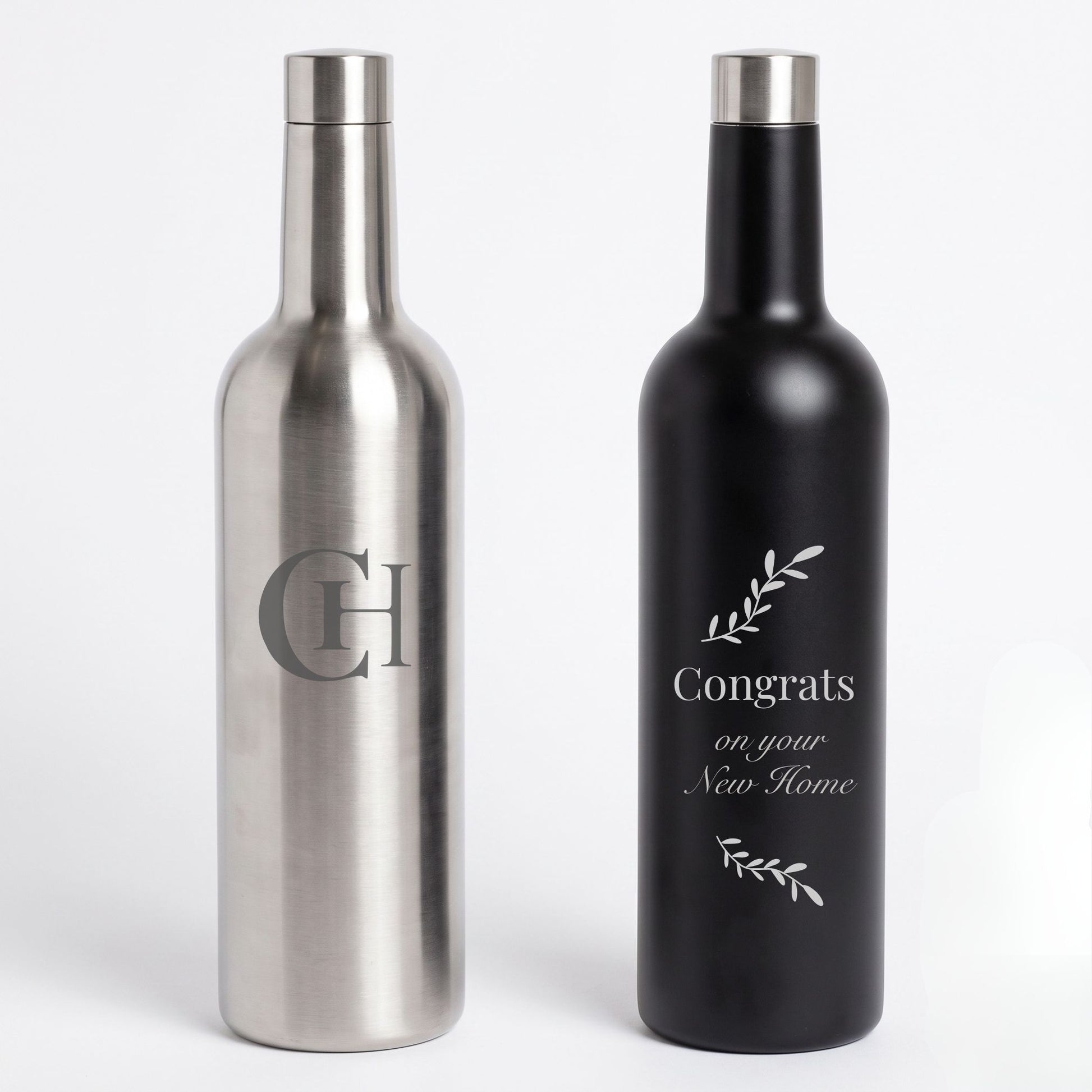 Two bottle-shaped flaskson a light gray background, one brushed silver with a large engraved monogram and one matte black with a white 'Congrats on your New Home' design.