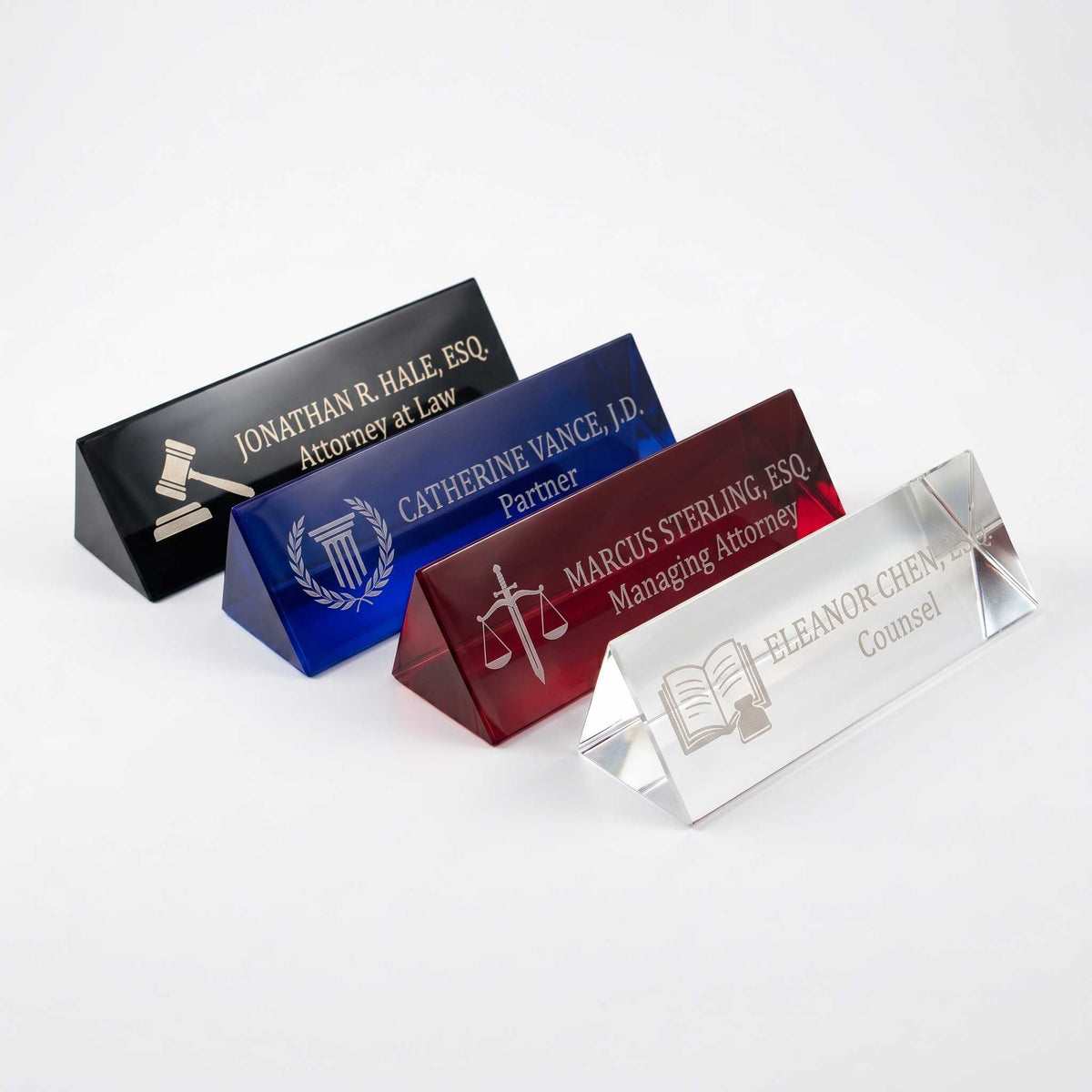 Four personalized heavy crystal nameplates for lawyers, shown in black, blue, red, and clear glass on a white background.
