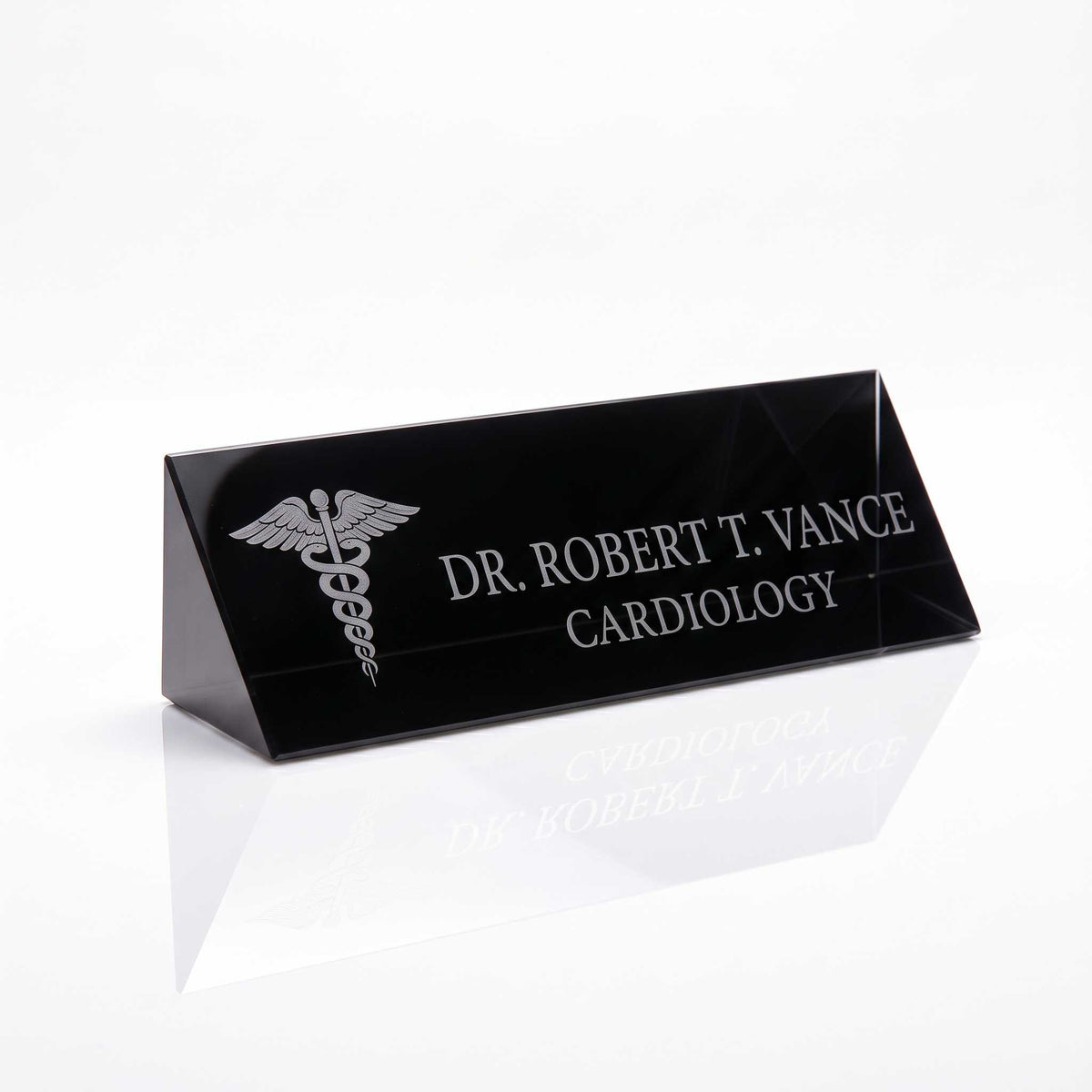 A black rectangular crystal nameplate with a tapered triangular base, featuring engraved silver text reading 'DR. ROBERT T.