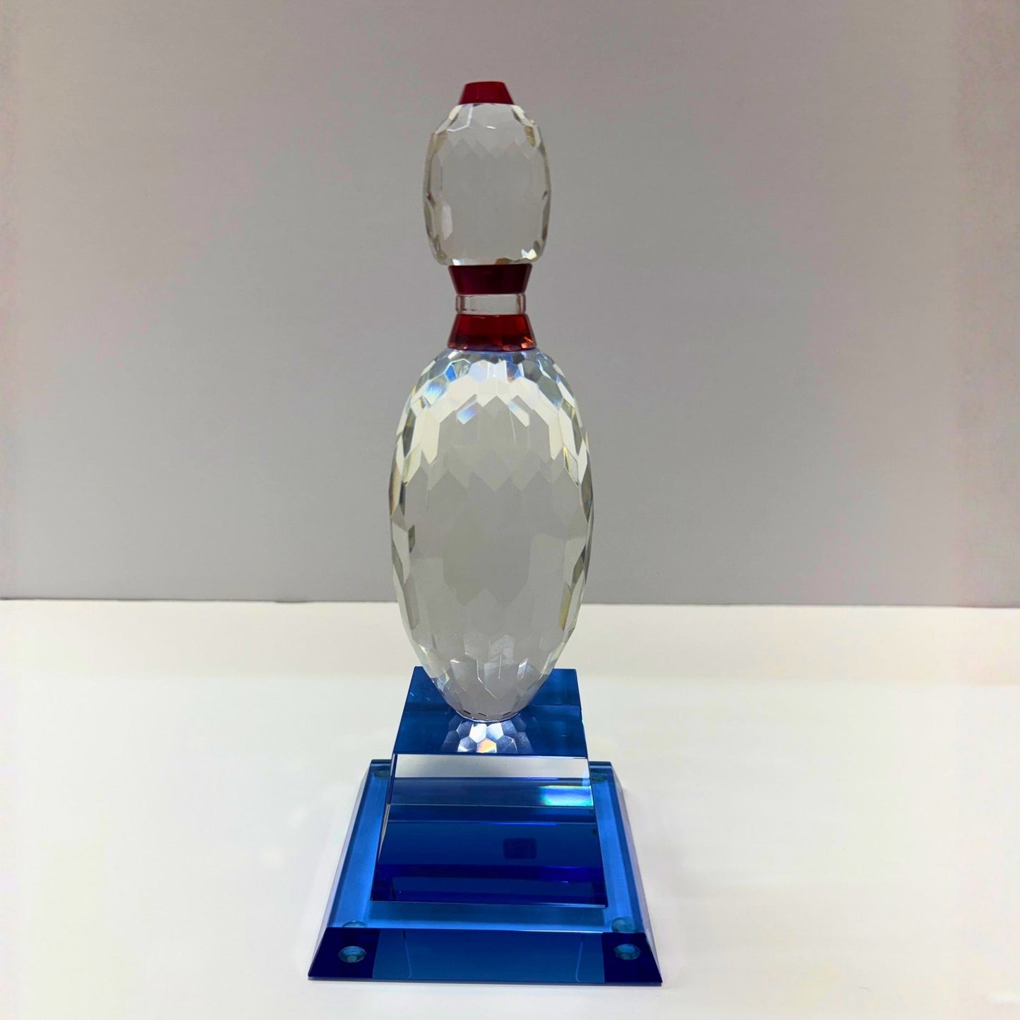 Crystal bowling pin on a blue base against a gray background