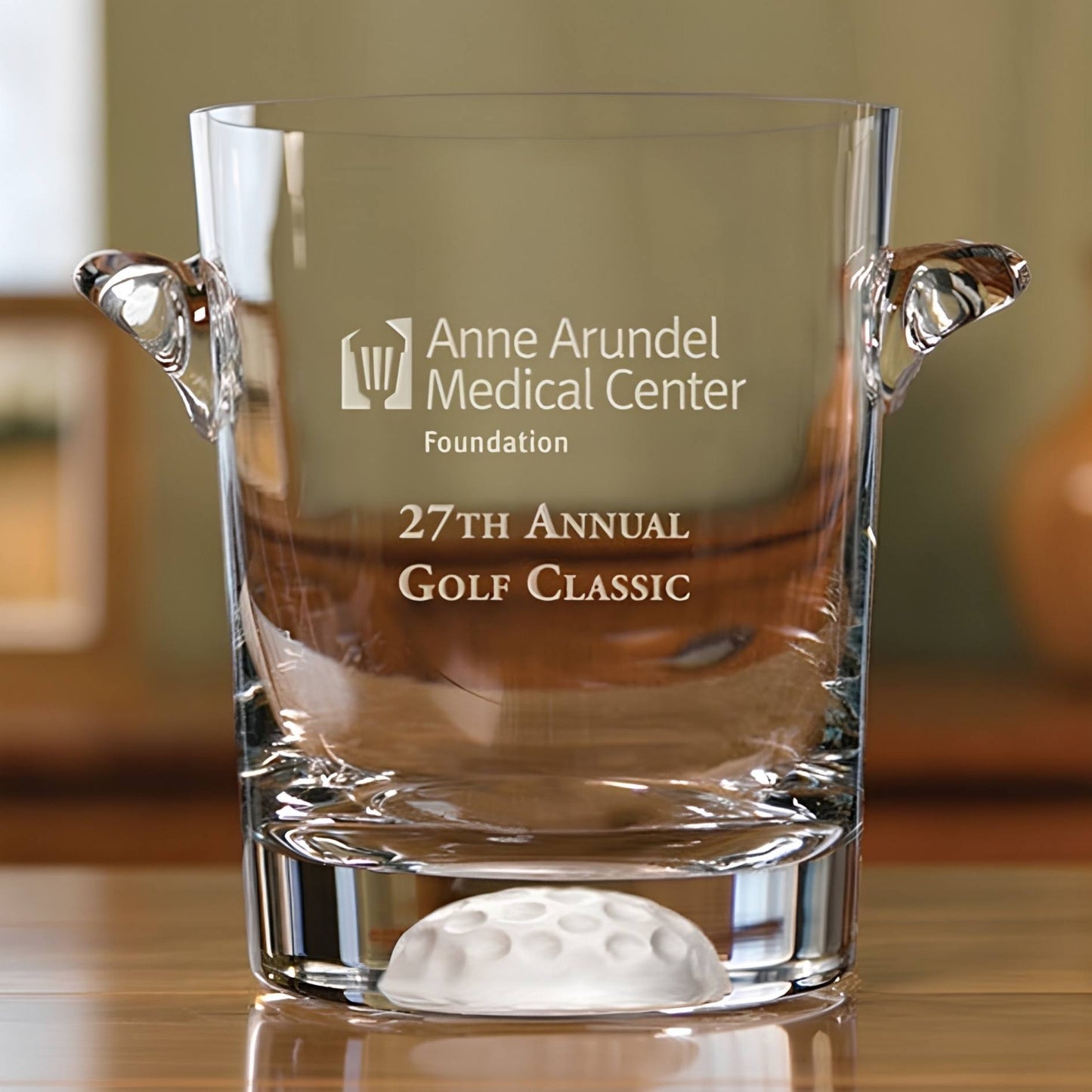 Clear glass ice bucket with engraved text on a wooden surface