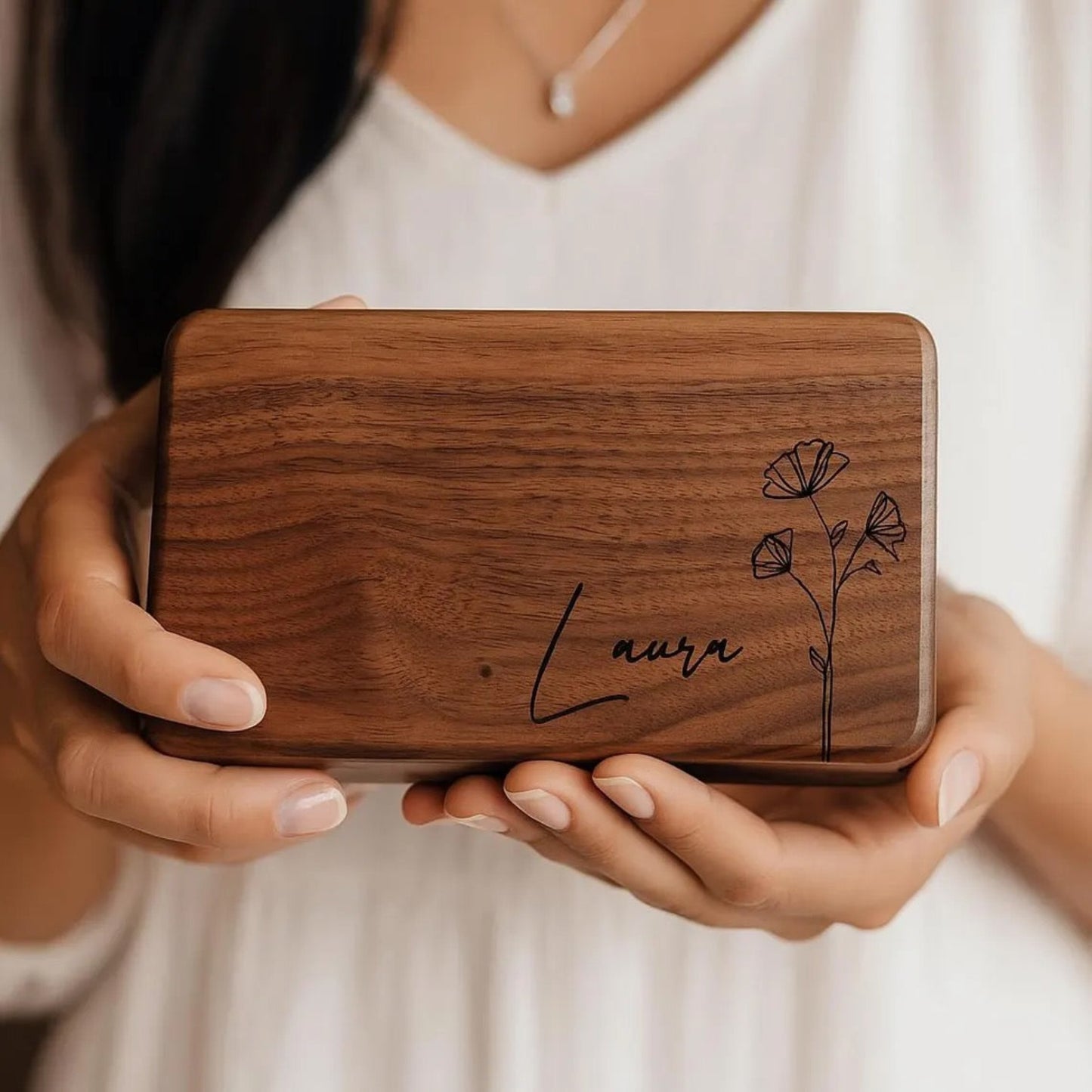 Wooden box with engraved name and floral design held by a person