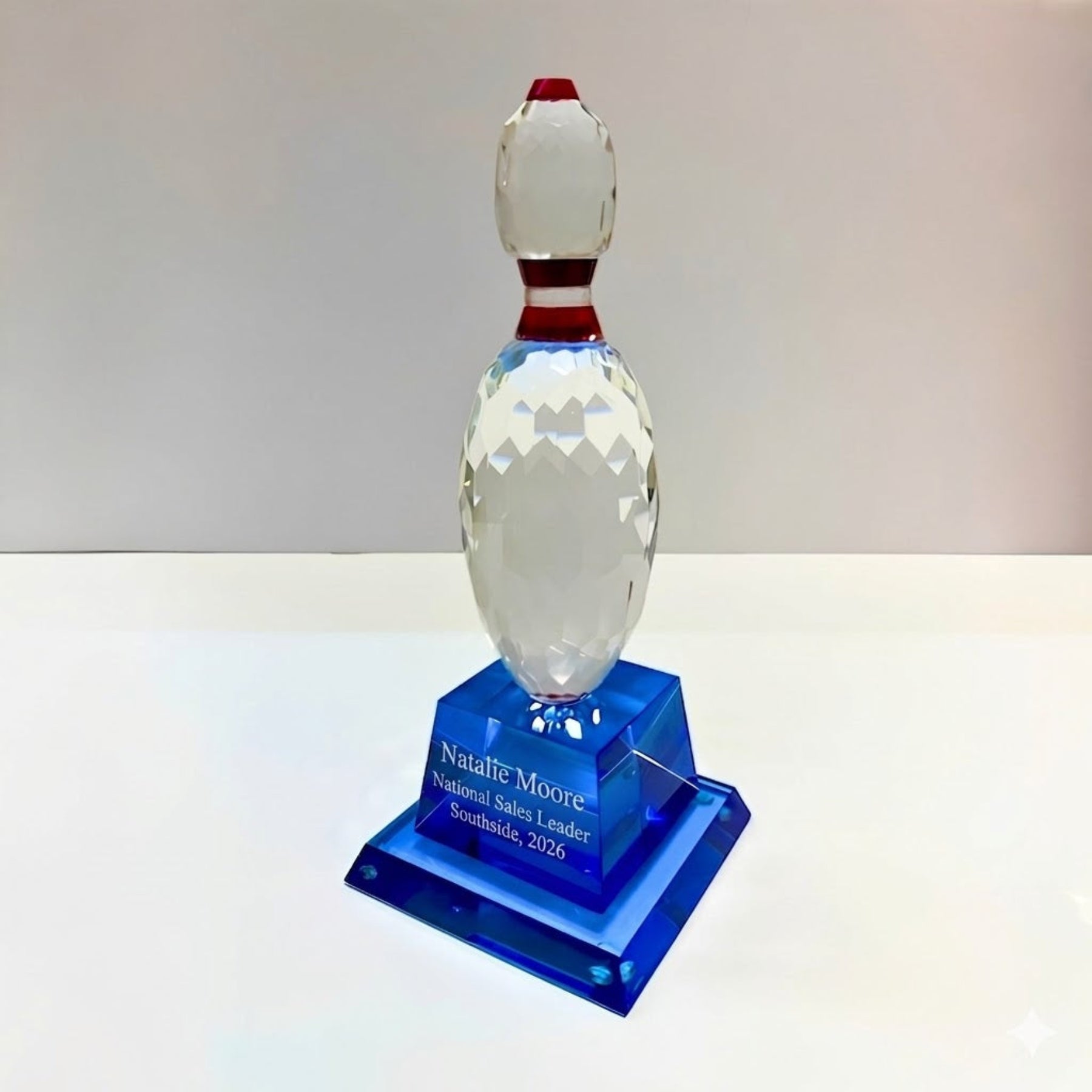 Crystal bowling pin award on a blue base with engraved text